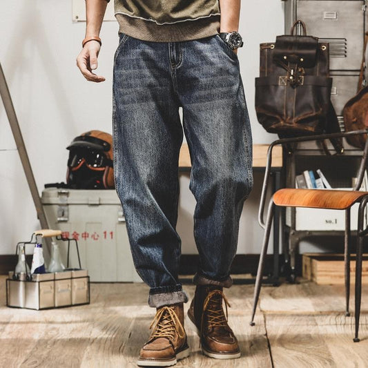 Person wearing blue jeans and brown boots in an indoor setting with furniture and equipment.