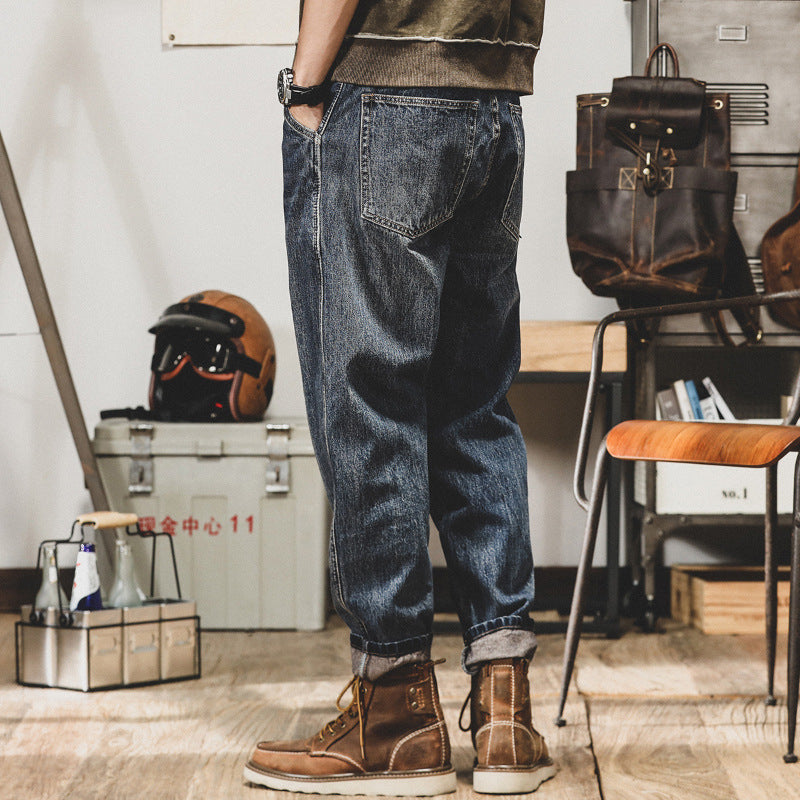 Person wearing blue jeans and brown boots in an indoor setting with a helmet and storage box in the background.